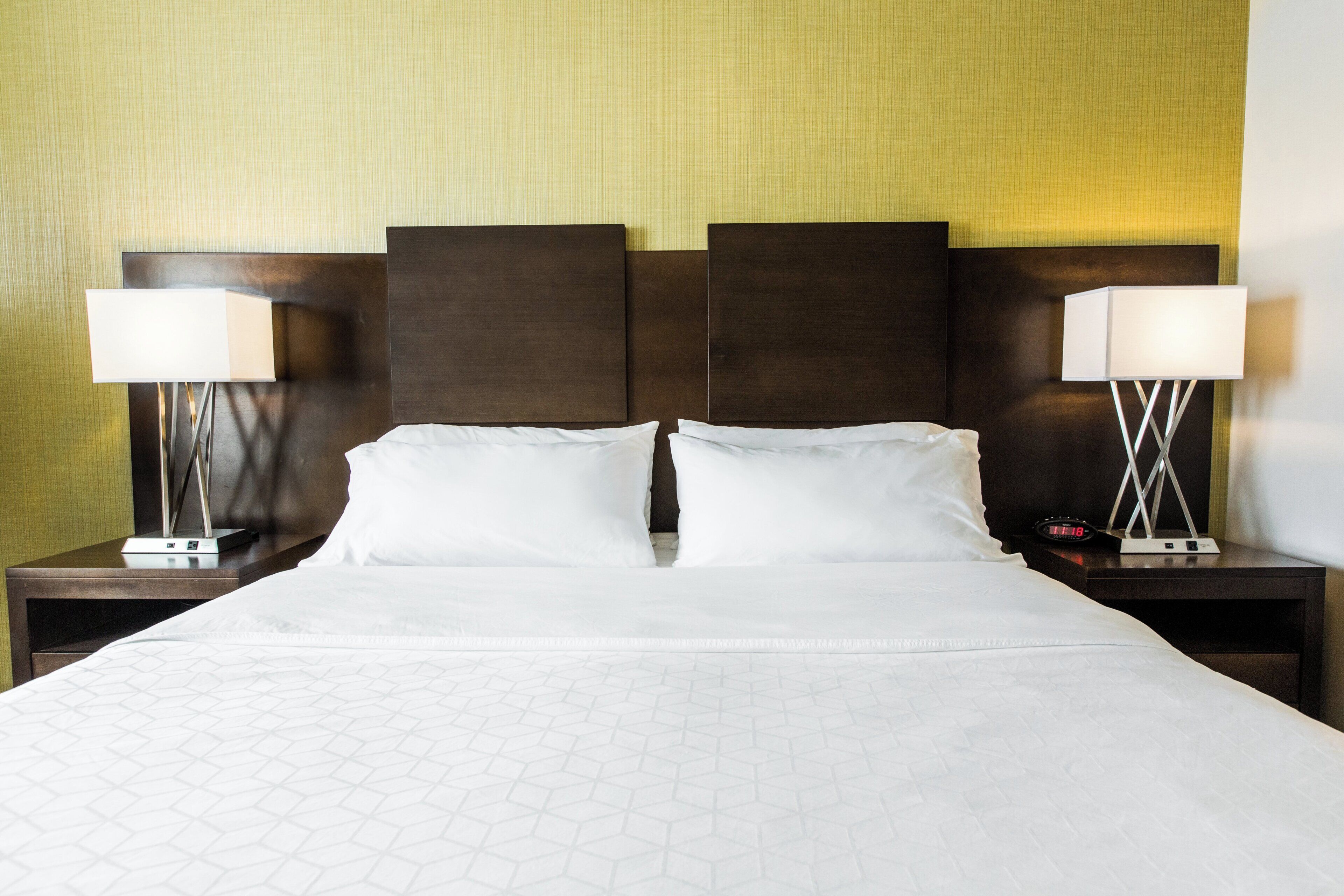 A hotel room with a large bed, two bedside tables, and two lamps.