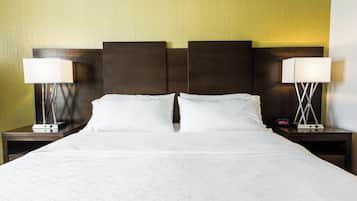 A hotel room with a large bed, two bedside tables, and two lamps.