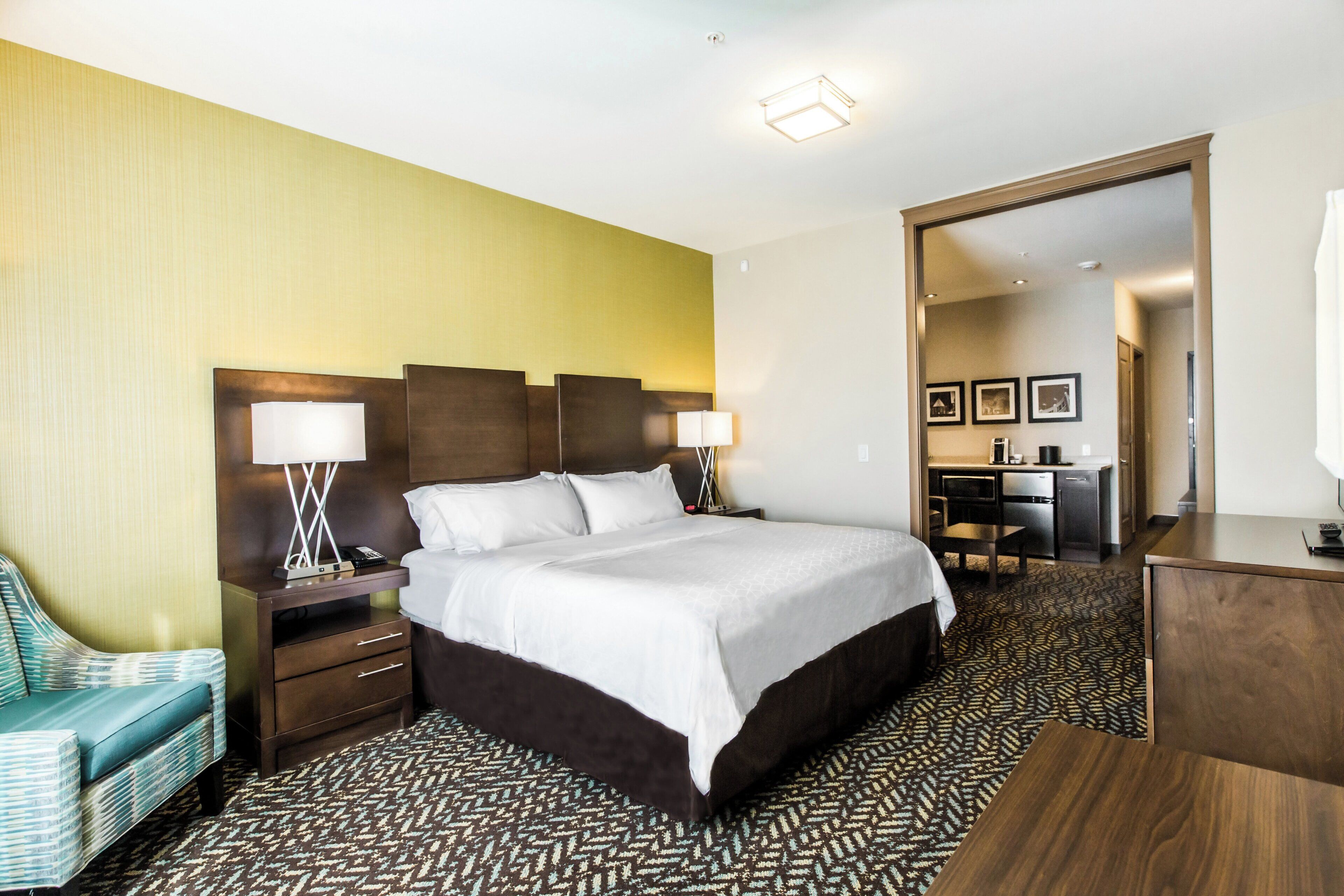 A hotel room with a large bed, bedside tables, a desk, and a chair.