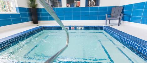 An indoor swimming pool with blue tiled walls and a clear water surface.