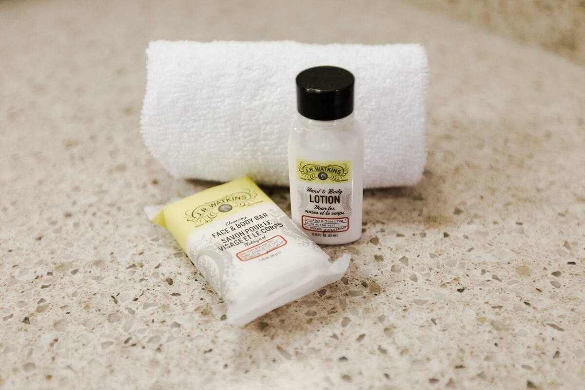 A bathroom with a white towel and two toiletries on a speckled countertop.