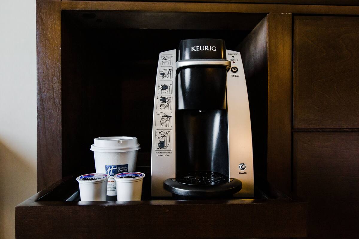 A Keurig coffee maker with instructions and two disposable coffee cups.