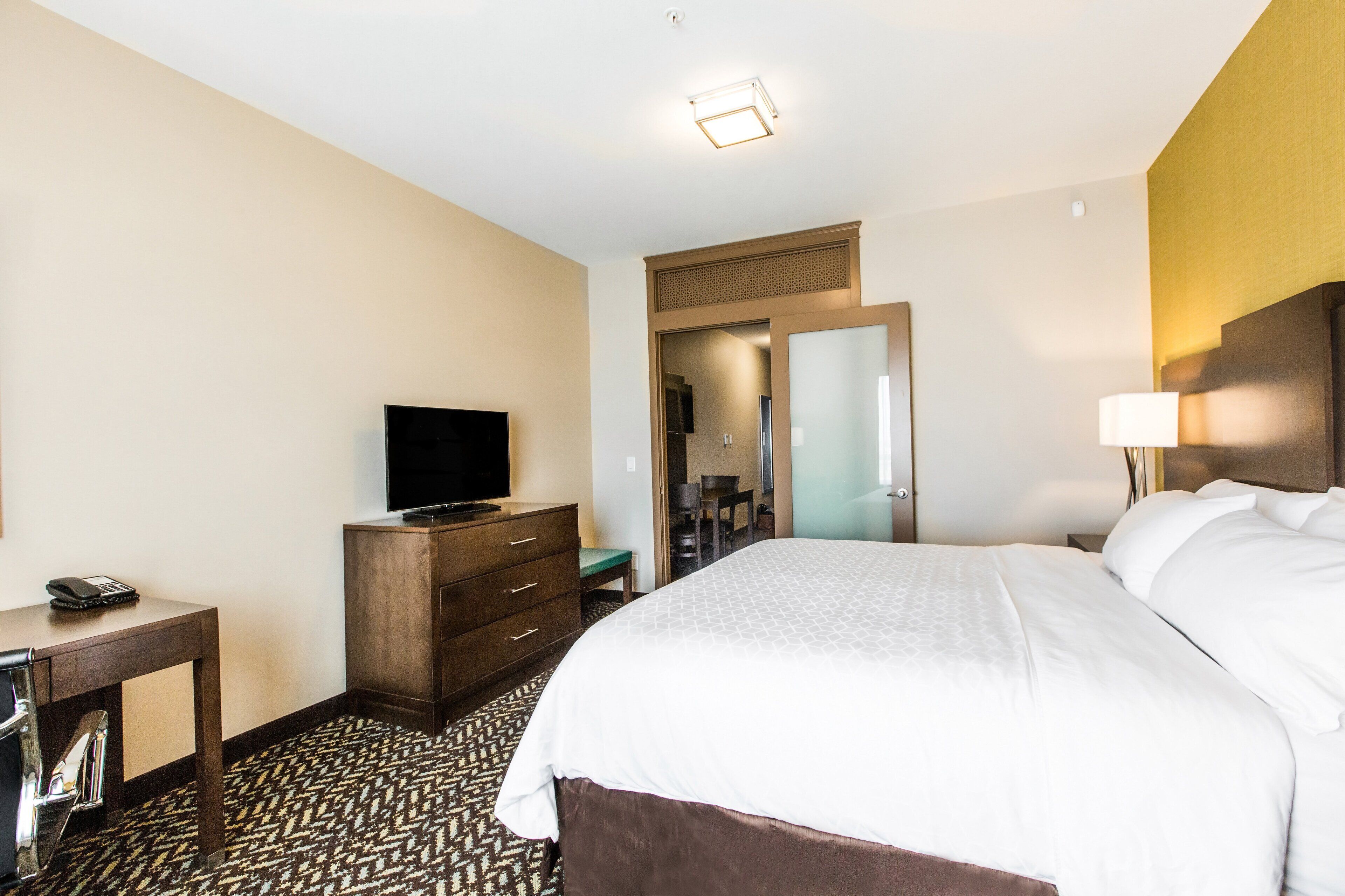 Une chambre d’hôtel équipée d’un lit, d’une télévision, d’un bureau avec un téléphone et d’un miroir.