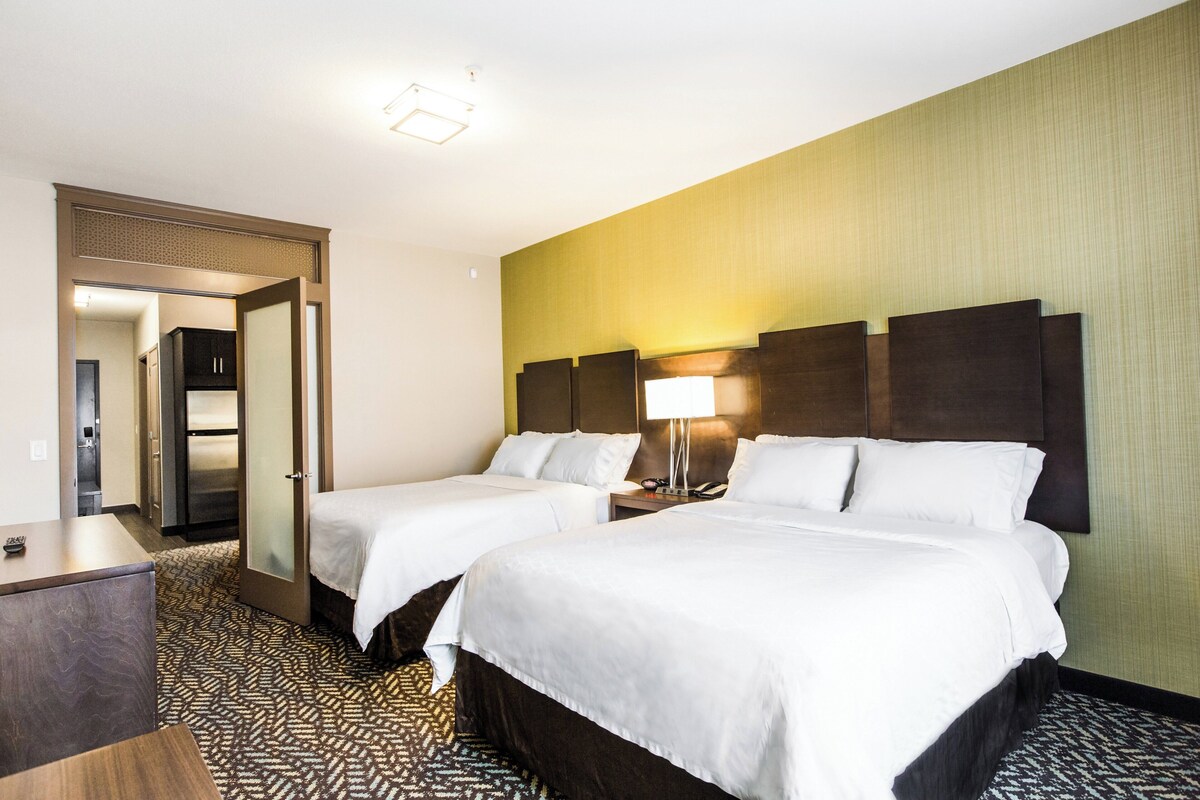 A hotel room with two beds, a desk, and a wardrobe.