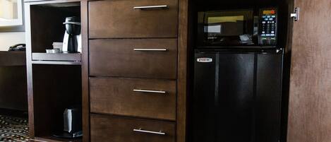 A wooden cabinet with a microwave and coffee maker inside.