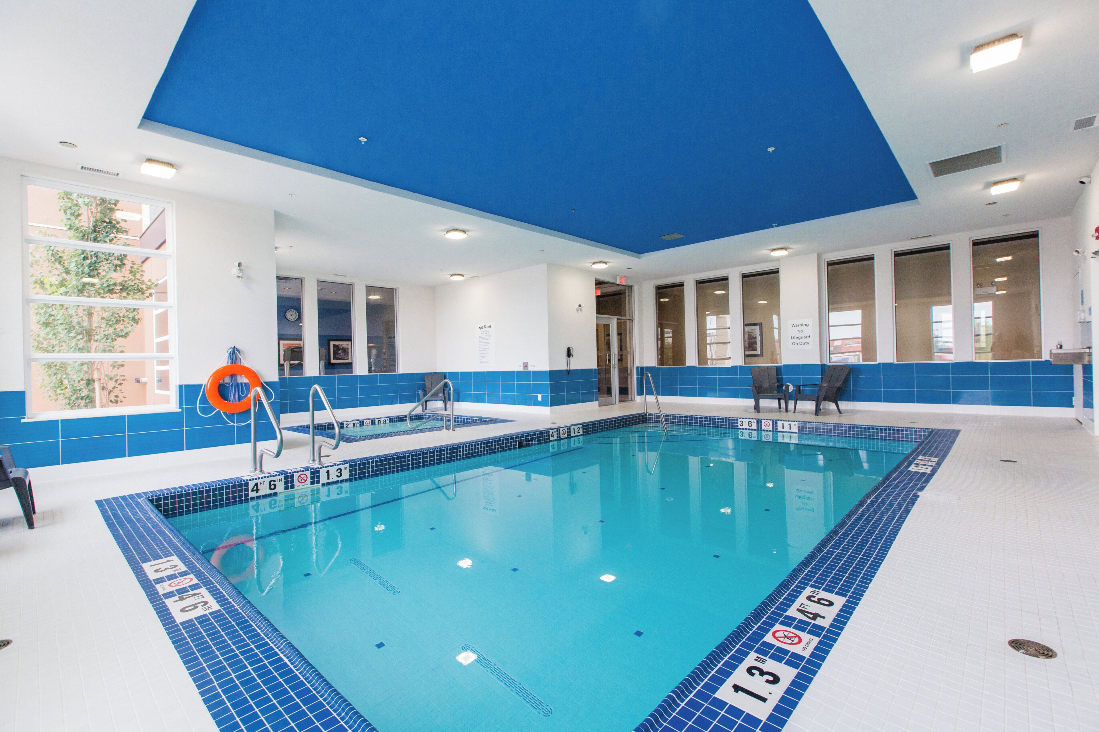 Une piscine aux murs recouverts de carreaux bleus et au plafond blanc.
