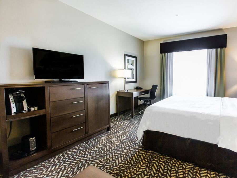 A hotel room with a bed, a desk, a television, and a coffee machine.