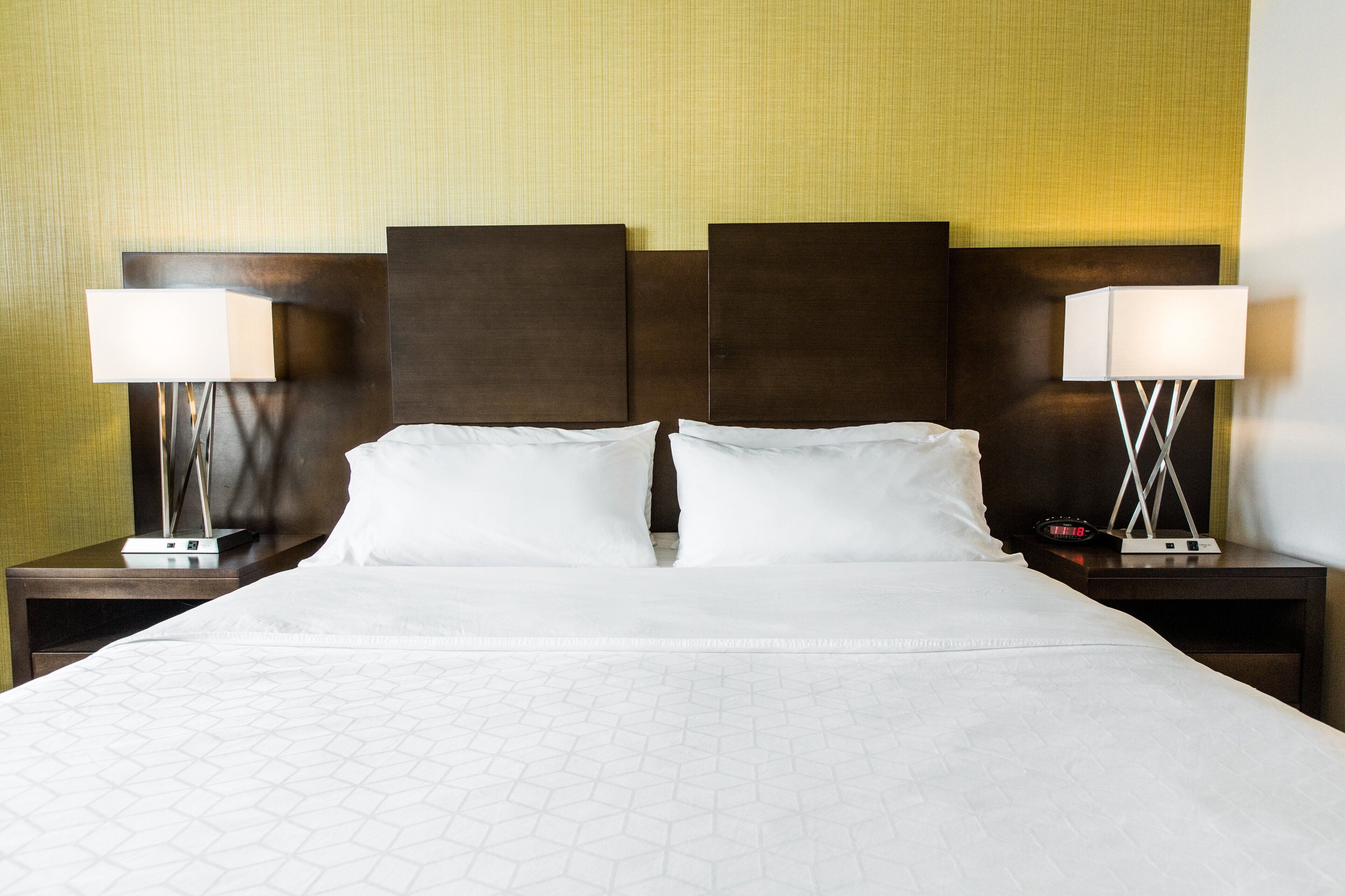 A hotel room with a large bed, two bedside tables, and two wall-mounted lamps.
