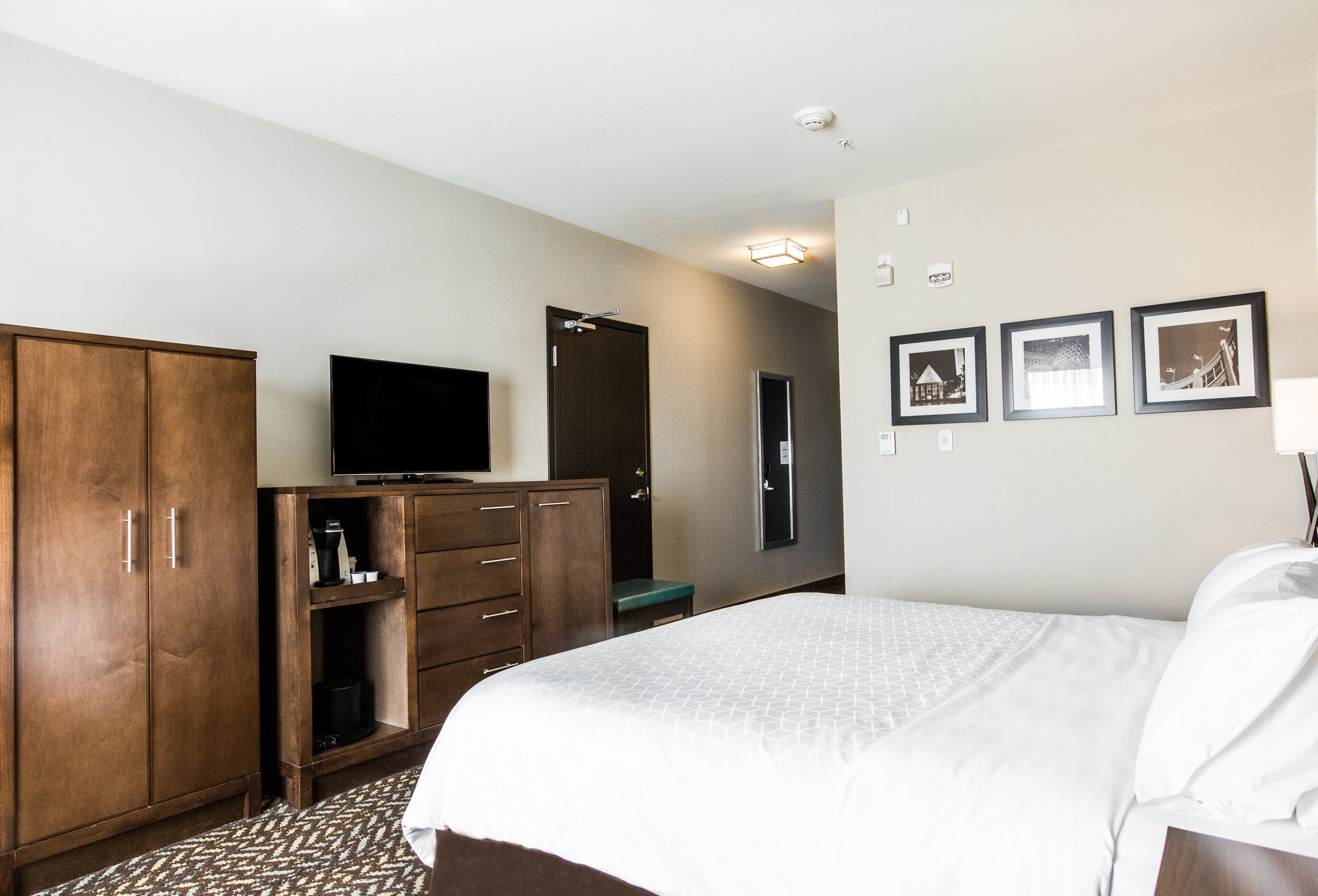 Una habitación de hotel con cama, armario, televisor, escritorio y una pequeña zona de estar.