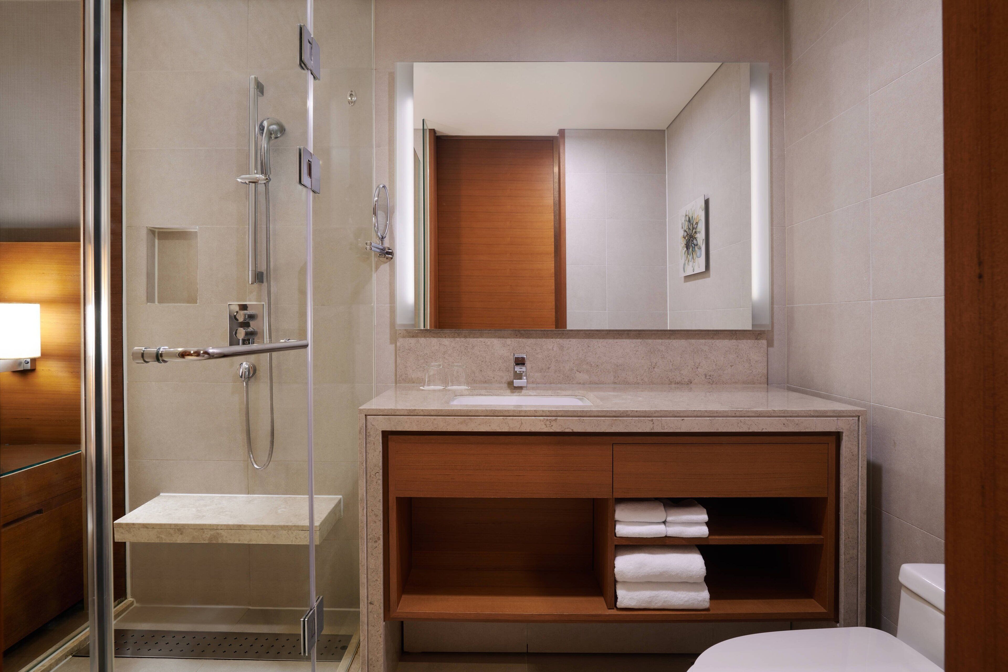 A modern bathroom with a glass-enclosed shower, a wooden vanity with a sink, and a large mirror above the vanity.