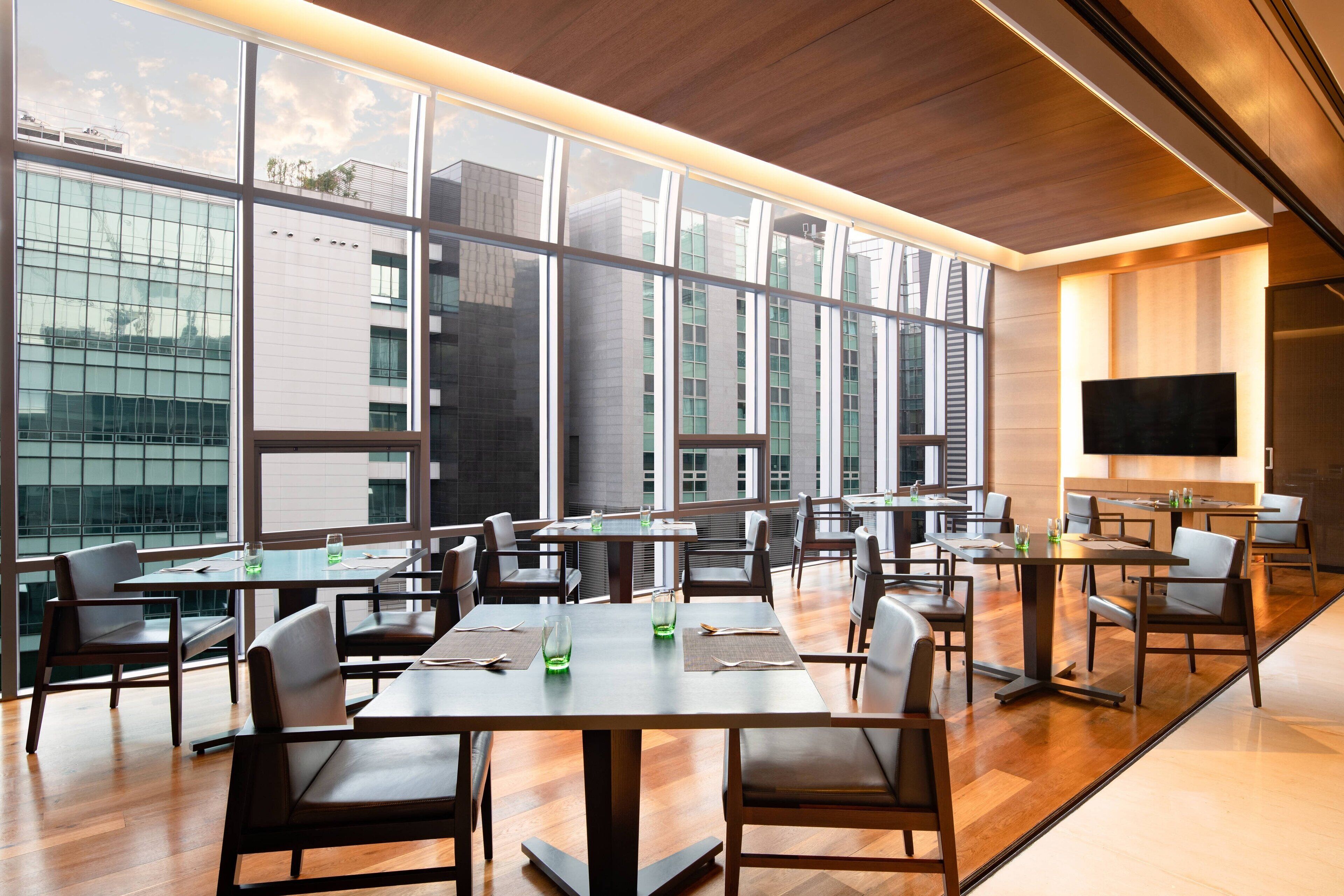 A modern dining area with large windows, wooden floors, and contemporary furniture.