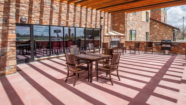 Eine Terrasse im Freien mit einer Steinmauer, einer Holzpergola und einem Grillbereich.