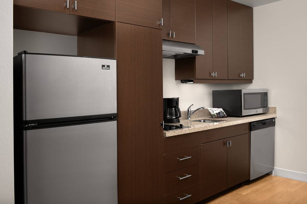 A kitchen with a stainless steel refrigerator, a microwave, a coffee maker, and a dishwasher.