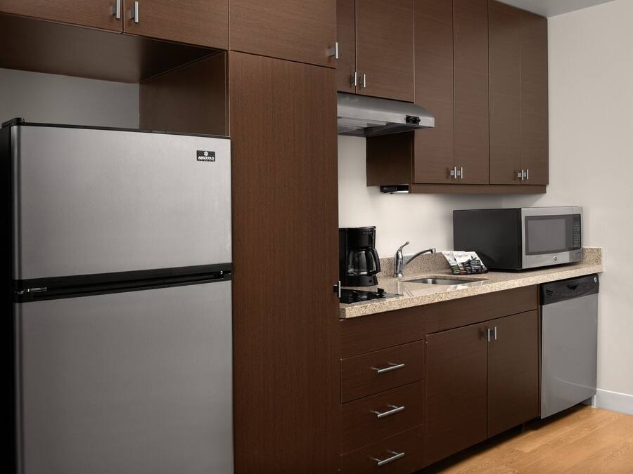 Eine Küche mit Edelstahl-Kühlschrank, Mikrowelle, Kaffeemaschine und Geschirrspüler.