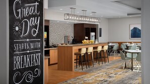 Eine moderne Hotelhalle mit Barbereich, Frühstücksbereich und Sitzgelegenheiten.