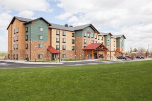 A multi-story hotel with a stone facade, green and beige exterior, and a red roof. - TownePlace Suites by Marriott Cheyenne SW/Downtown Area (Cheyenne)
