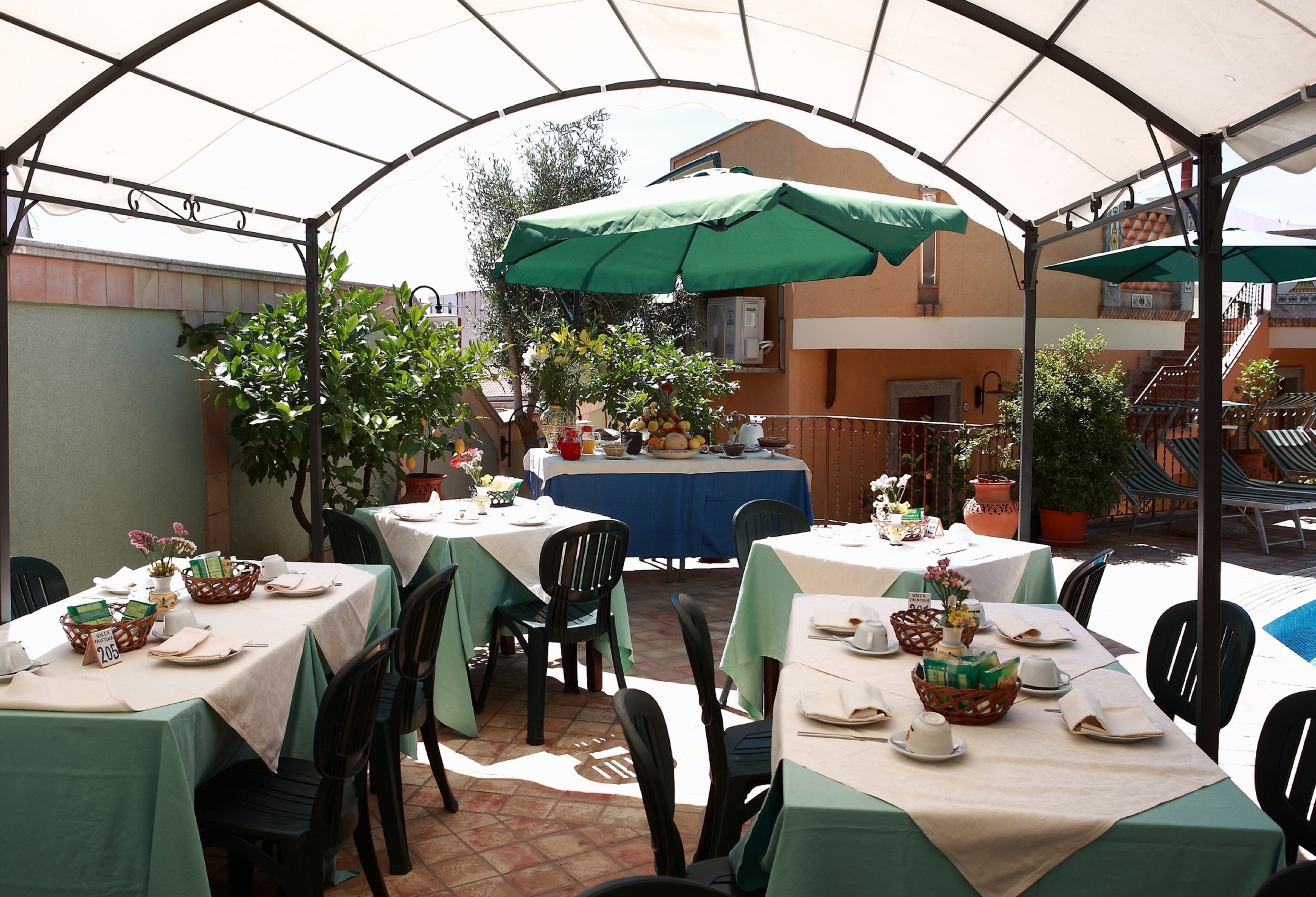 Une terrasse extérieure avec des tables disposées pour les repas, protégées par des parasols et entourée de chaises.
