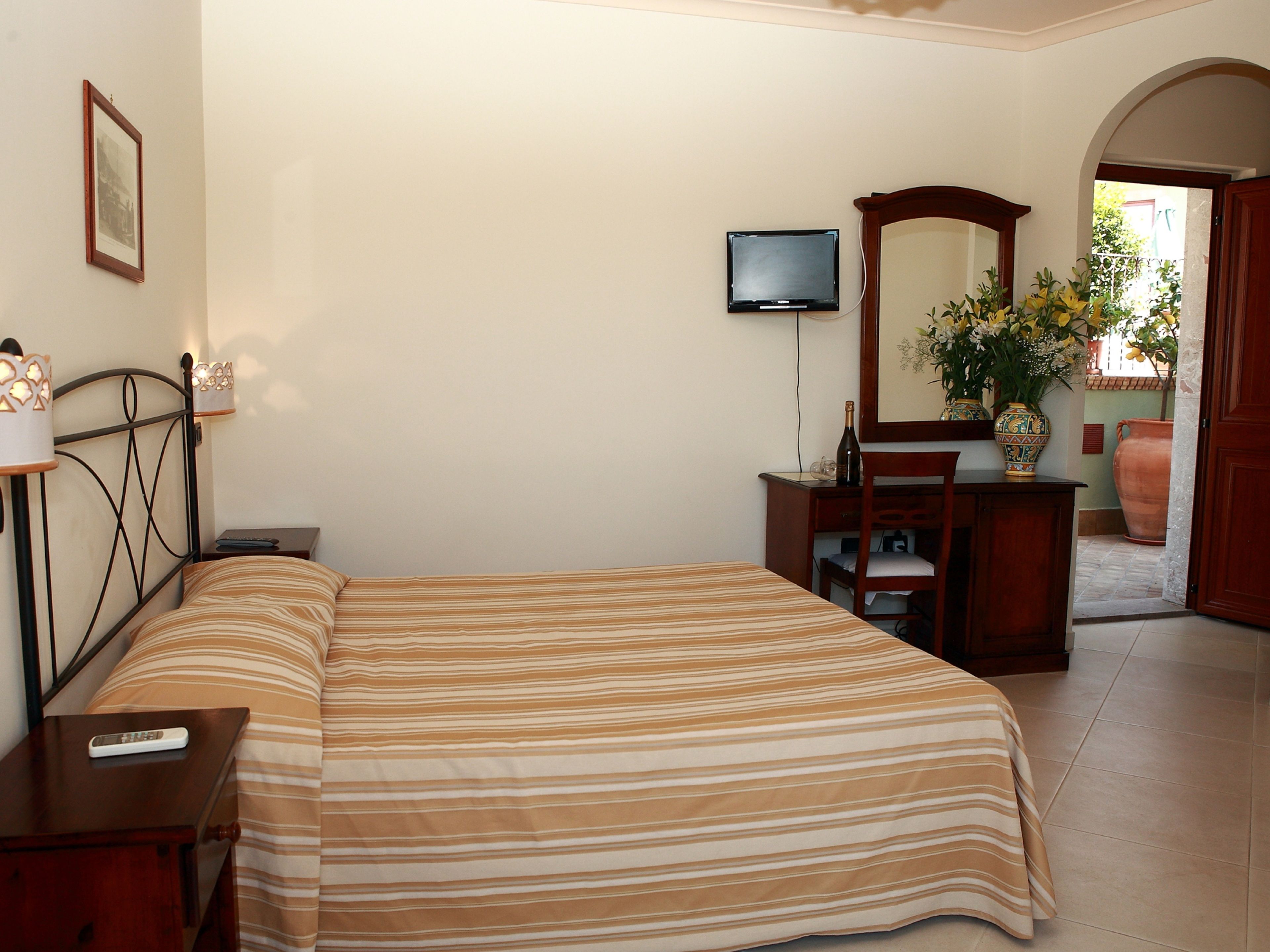 A bedroom with a bed, bedside tables, a dresser, a television, and a mirror.