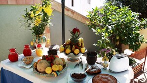 Een tafel met diverse etenswaren, waaronder fruit, koekjes en een taart, buiten opgesteld.