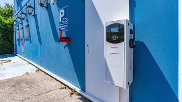 A blue building with a parking sign, a charging station, and a door with a lock.