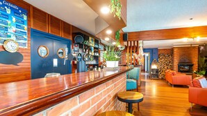 Zona de bar con mostrador de madera, un reloj y una pizarra con el menú.