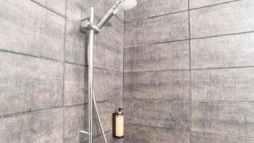 A shower with a handheld showerhead and a wall-mounted soap dispenser.