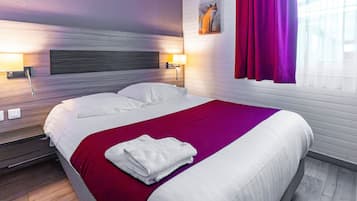 Una habitación de hotel con cama, cabecera, mesita de noche, ventana con cortinas y un cuadro en la pared.