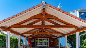 Un espacio exterior cubierto con estructura de techo de madera y puerta de vidrio.