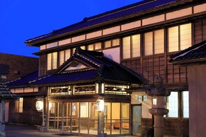 Un bâtiment japonais traditionnel, caractérisé par un toit recouvert de tuiles, une structure en bois et de grandes fenêtres.