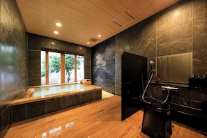 A modern bathroom with a wooden floor, a large mirror, a bathtub, and a shower area. - Wakamatsu Hot Spring Resort (Hakodate)