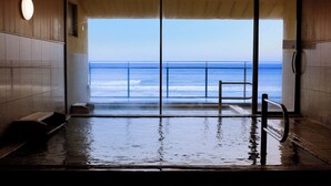 An indoor pool with a view of the ocean through large glass doors. - Wakamatsu Hot Spring Resort (Hakodate)