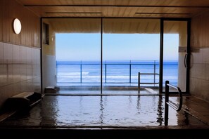 An indoor pool with a view of the ocean through large glass doors. - Wakamatsu Hot Spring Resort (Hakodate)