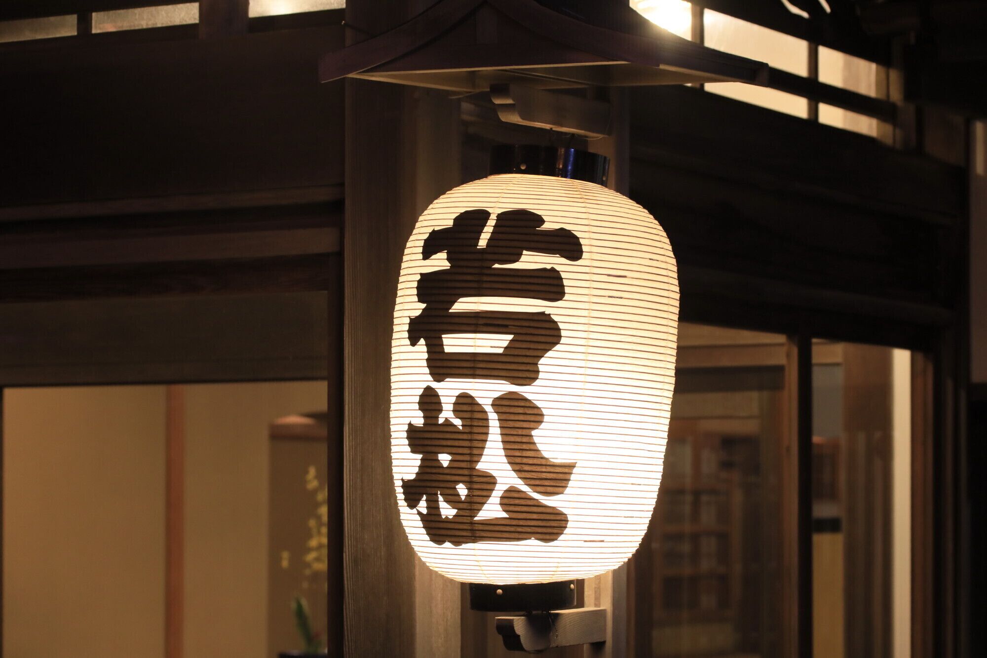 A traditional Japanese lantern with calligraphy, mounted on a post.
