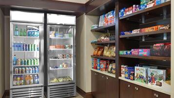 A vending machine stocked with beverages and snacks, and shelves with packaged goods.