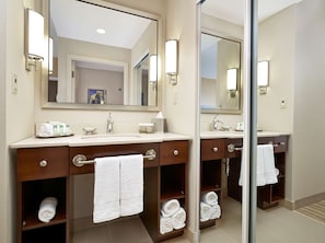 Bathroom features a large mirror, sink, and two cabinets with a towel rack.