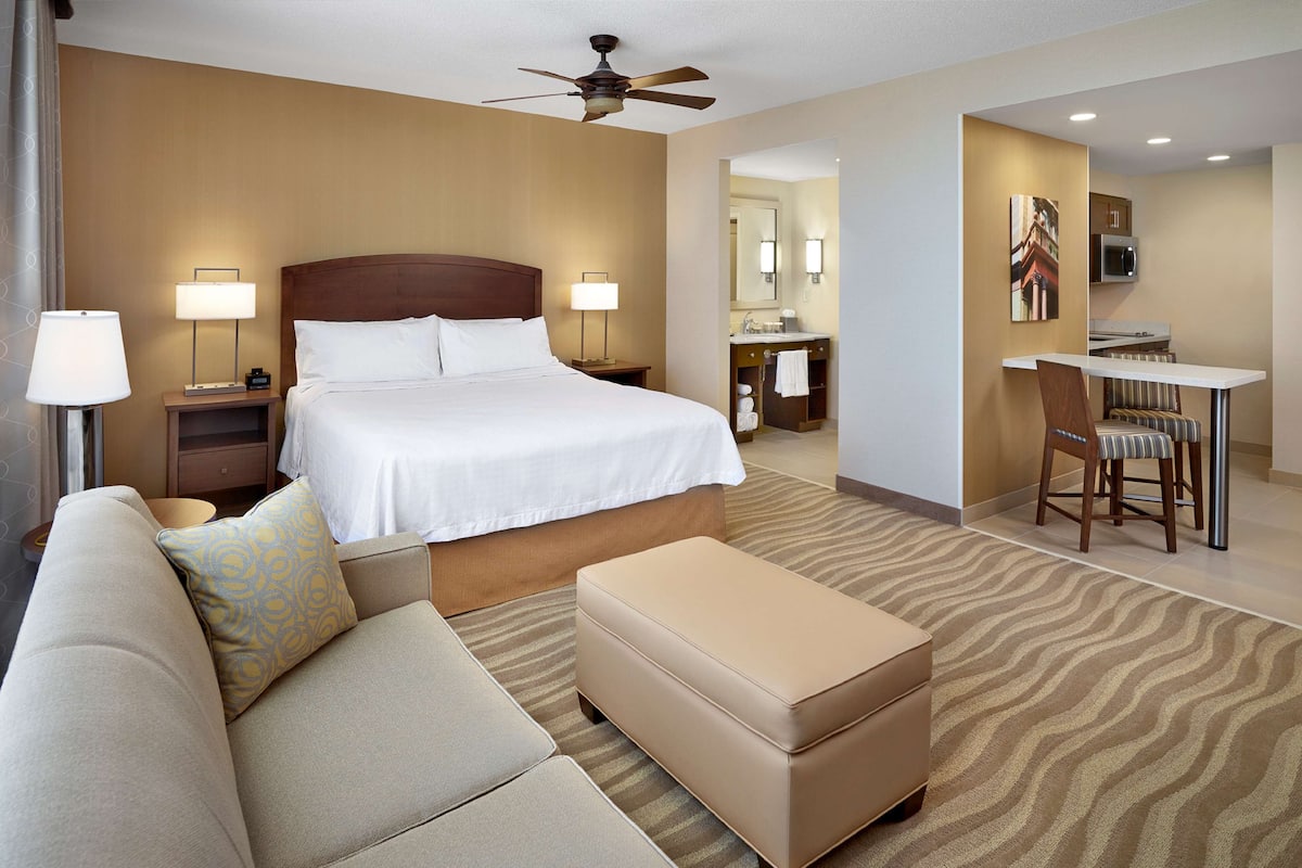 A hotel room with a bed, a sofa, a desk, and a chair.