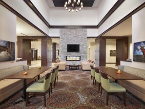 Relax and socialize in our elegantly designed lobby, featuring a central seating area, large TV, fireplace, and artwork on display.