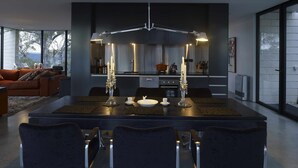 A modern dining area with a central table, four chairs, and a chandelier.