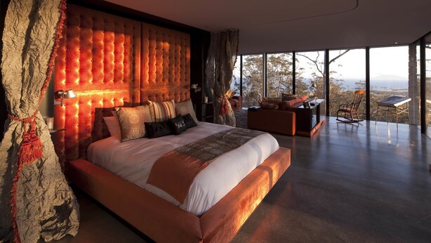 A modern bedroom with a large bed, a view of the outdoors, and a cozy seating area.