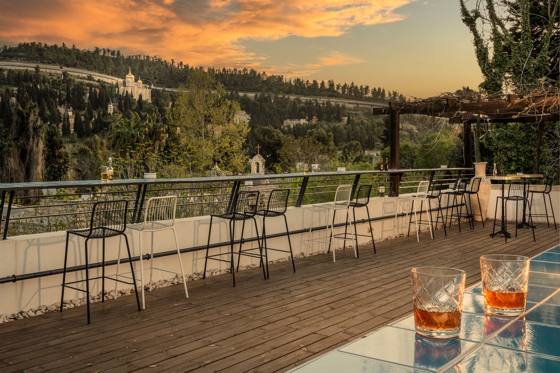 A terrace with outdoor seating and a view of a hill with a church.
