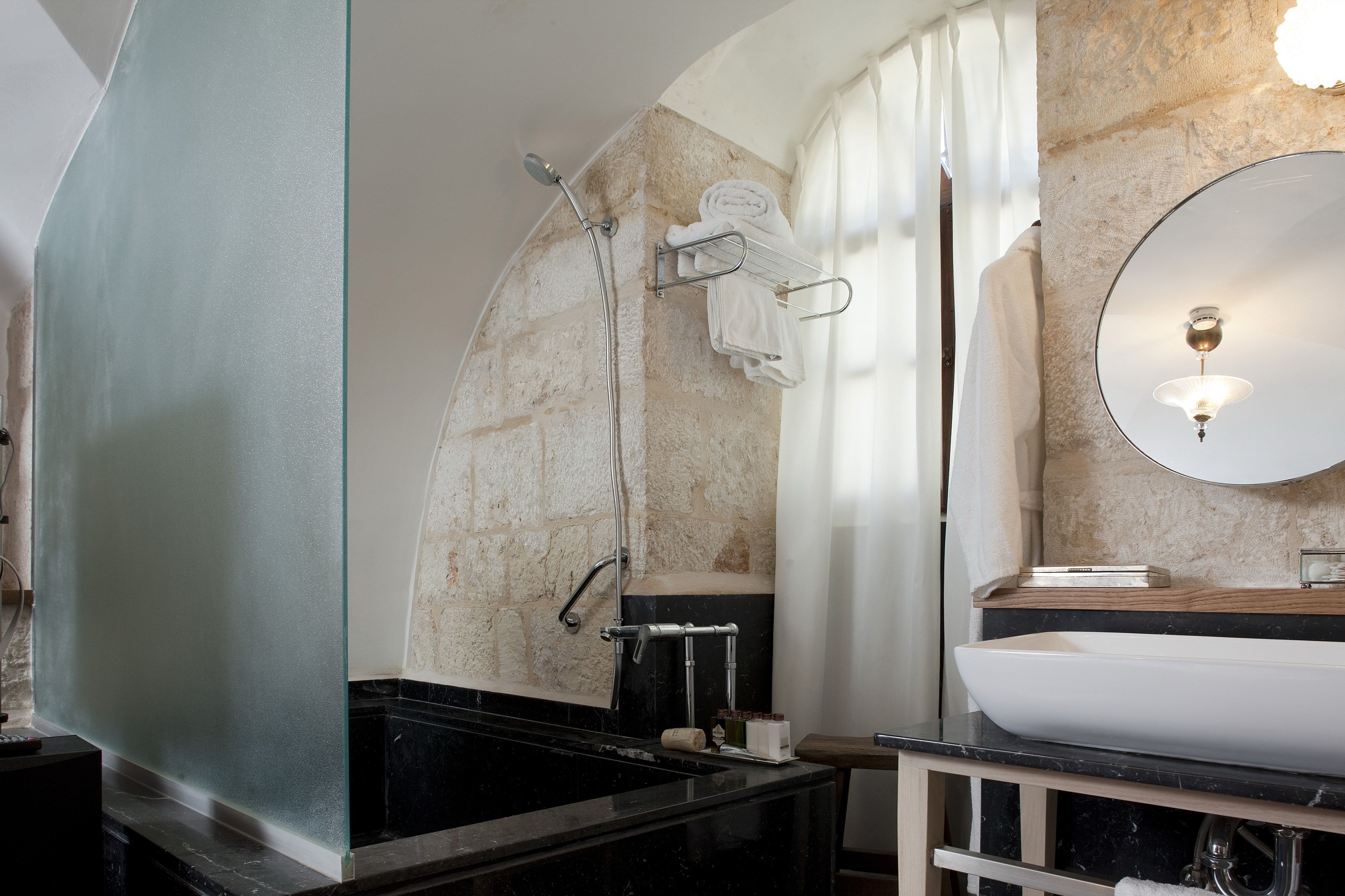 A bathroom with a black bathtub, a white sink, a mirror, and a towel rack.