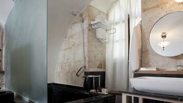 A bathroom with a black bathtub, a white sink, a mirror, and a towel rack.