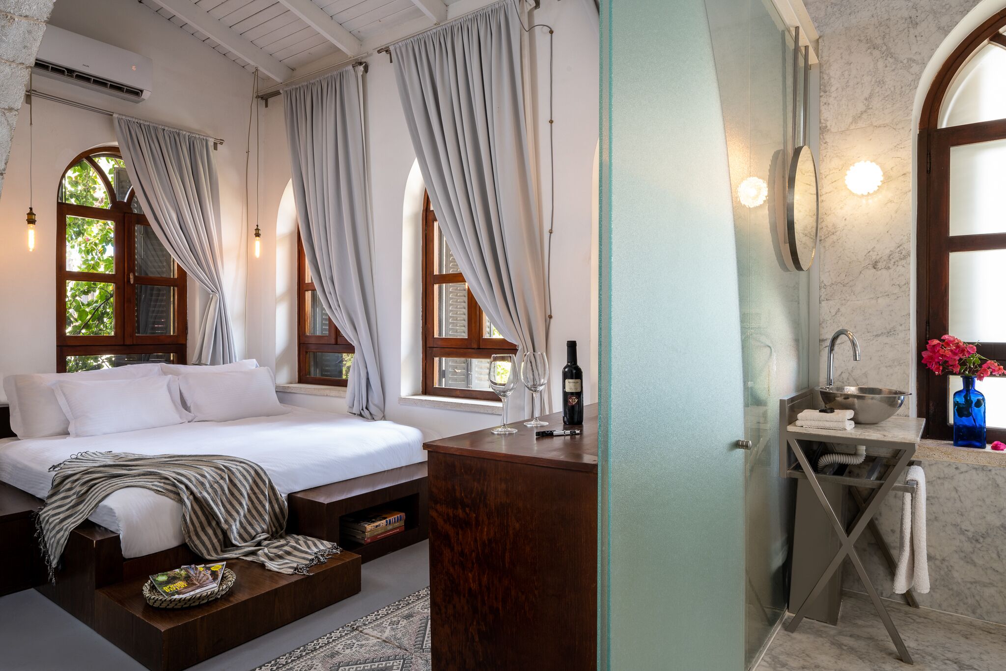 A bedroom with a bed, bedside table, and a window with curtains.