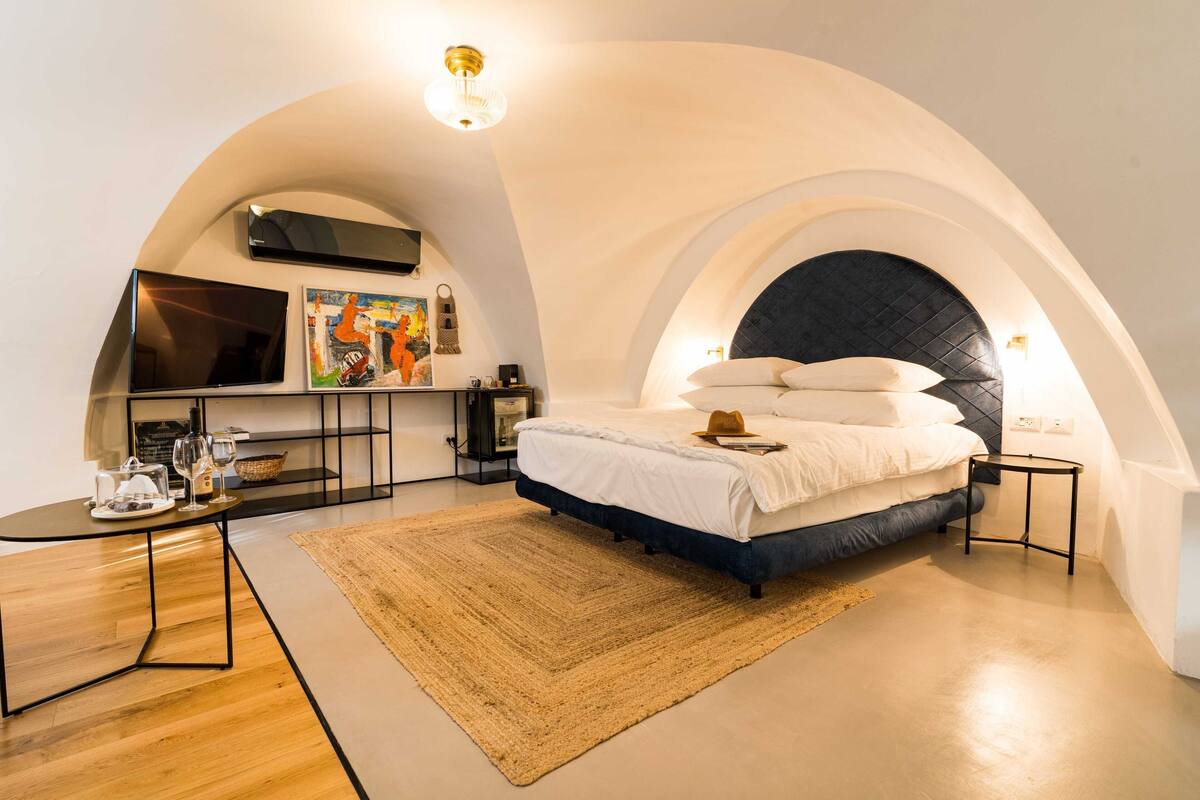 Un dormitorio moderno con una cama grande, un televisor y una zona de estar acogedora.