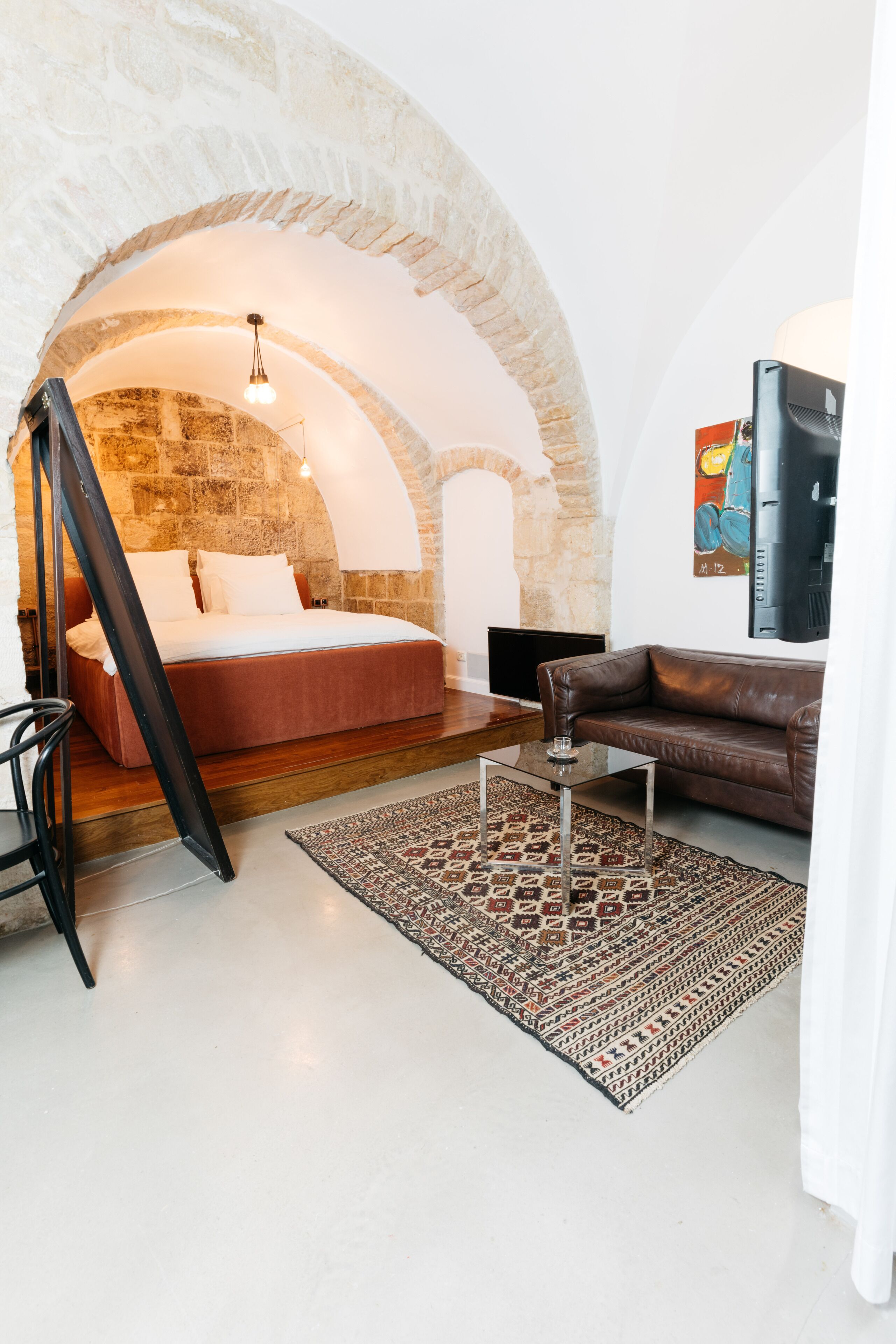 Una stanza accogliente con un letto, un divano in pelle, un tavolino da caffè e un tappeto decorato.