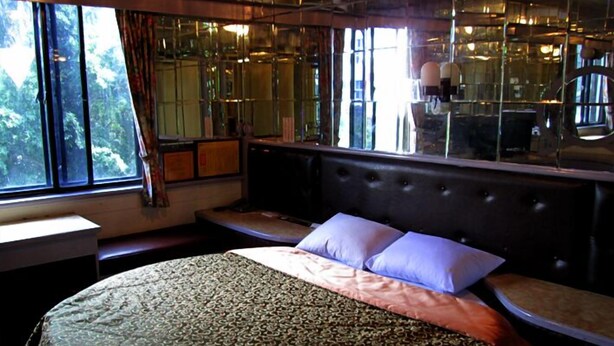A bedroom with a large bed, a bench, and a view of trees through the window. - One Plus One Hotel (Taipei)