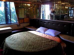 A bedroom with a large bed, a bench, and a view of trees through the window. - One Plus One Hotel (Taipei)