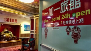 A hotel interior with a red carpet, a Buddha statue, and a sign indicating 24-hour open service. - One Plus One Hotel (Taipei)
