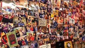 A wall covered with numerous photographs and travel-related signs, including destinations like Japan, Hawaii, and Australia. - One Plus One Hotel (Taipei)