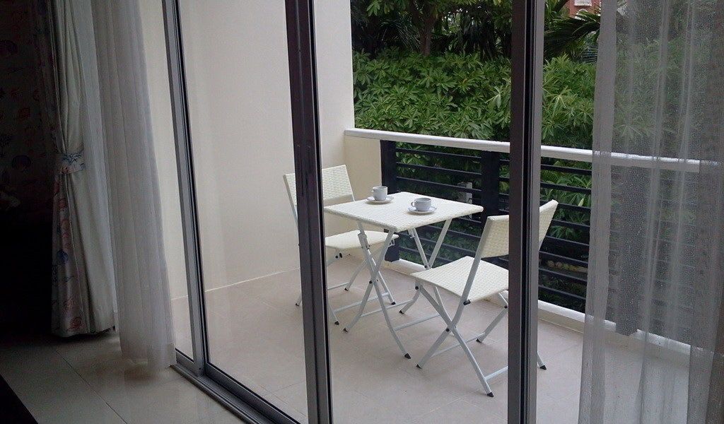 A balcony with a white table and chairs, a white cup, and a white saucer.